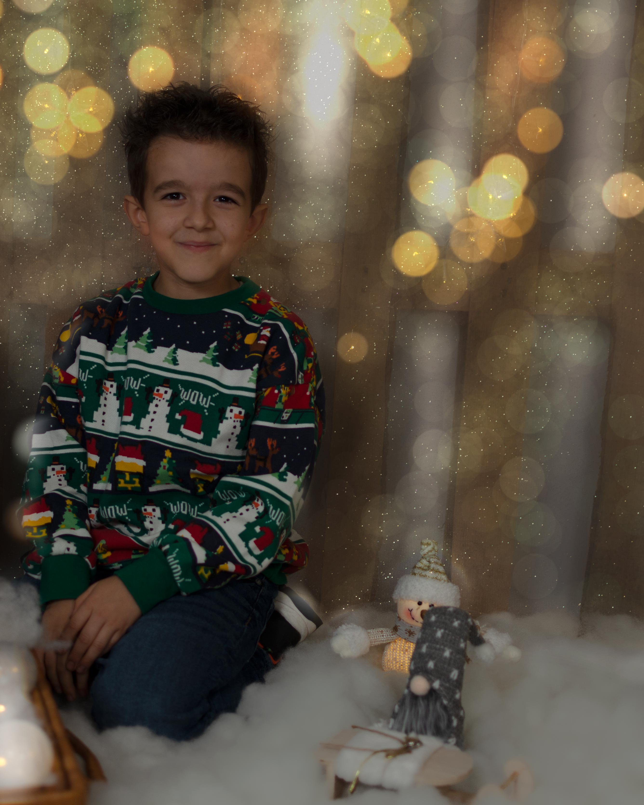 Niño con jersey navideño sosteniendo una cesta decorativa, rodeado de luces festivas y ambiente cálido.