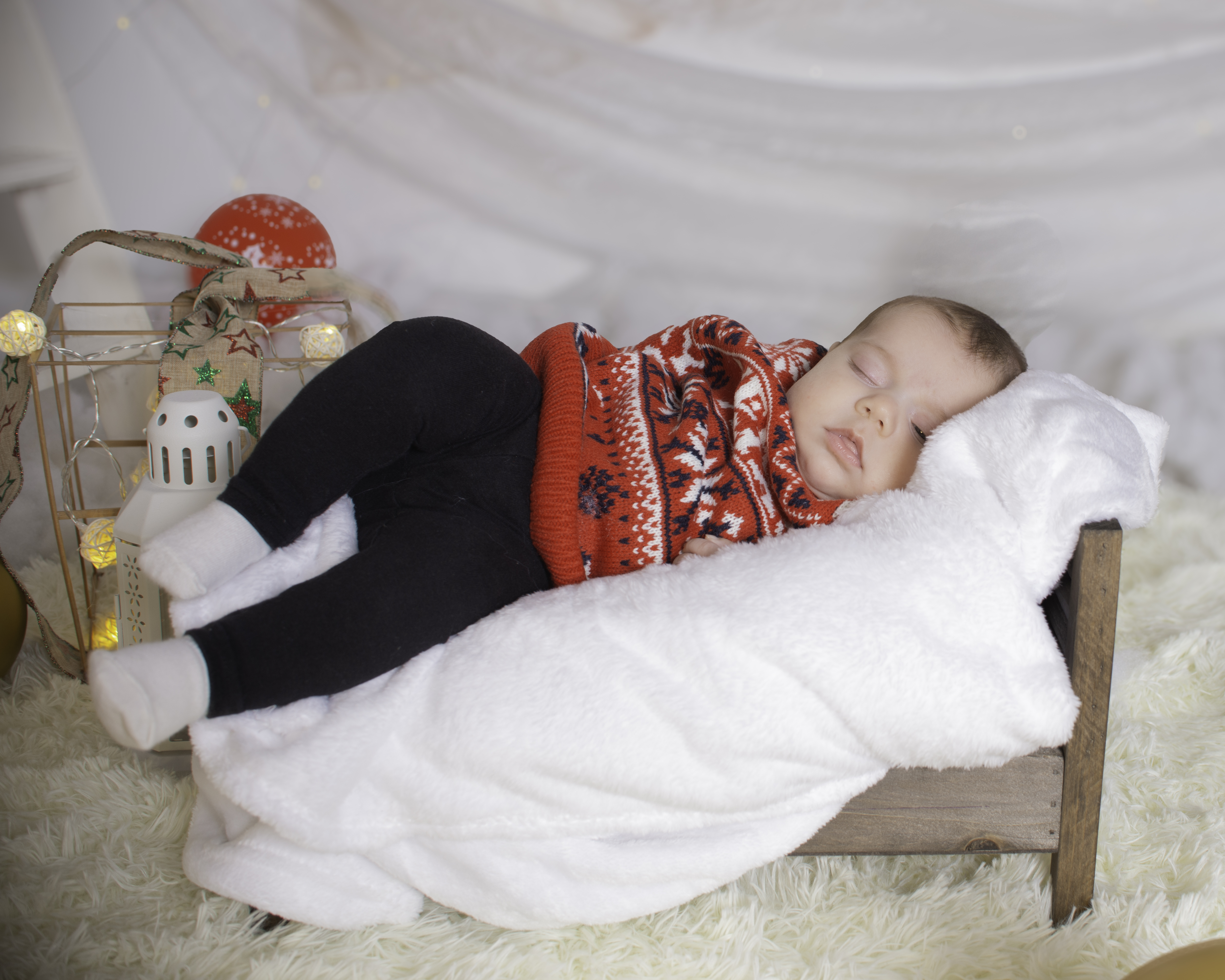 Retrato infantil en cama de madera con decoración festiva y luces cálidas