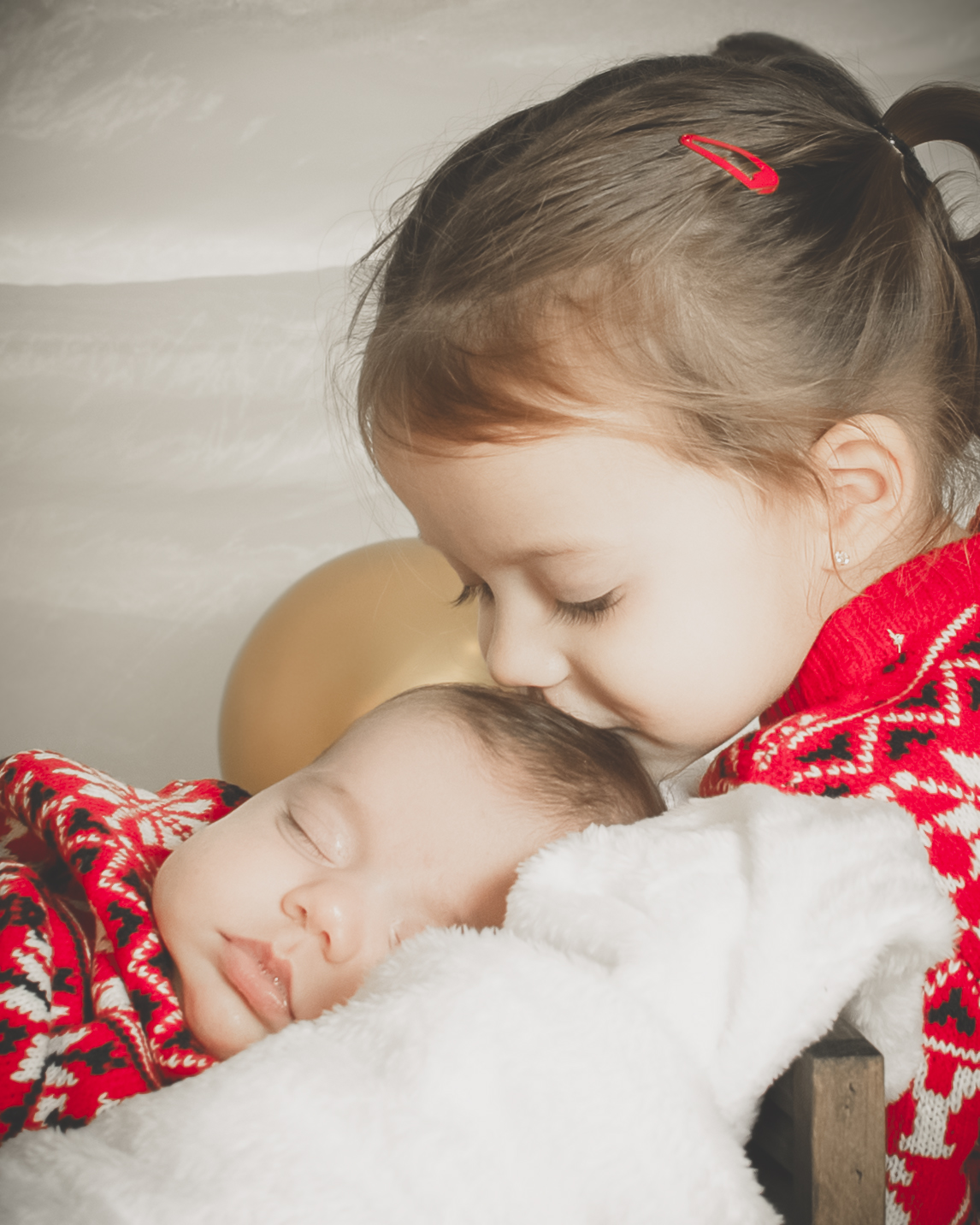 Bebé dormido envuelto en manta blanca, con conjunto rojo y blanco, transmitiendo ternura y calma