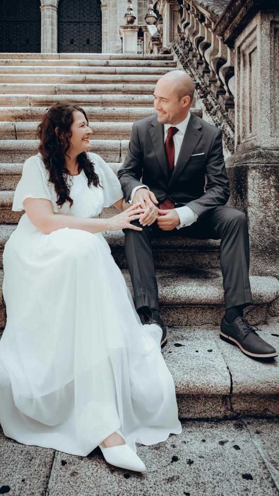 Pareja de novios sentada en las escaleras de la Catedral de San Martiño en Ourense durante su sesión fotográfica de boda.
